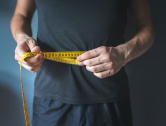 A man measing his waist with a tap and thinking about weight loss