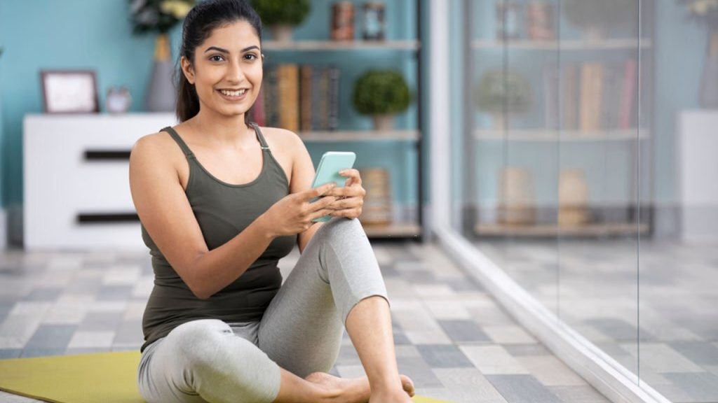 A Lady is sitting and holding the phone and smiling