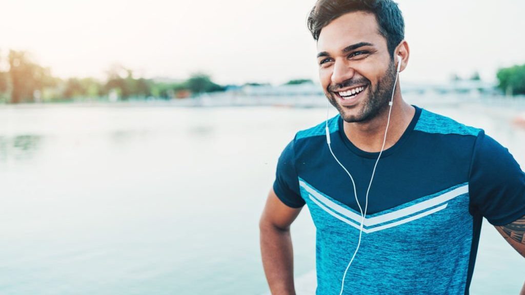 A man listing from the earphone and smiling.