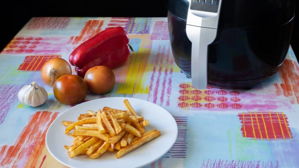 A plate with french fries, onions, tomatoes, and red capsicum on the table